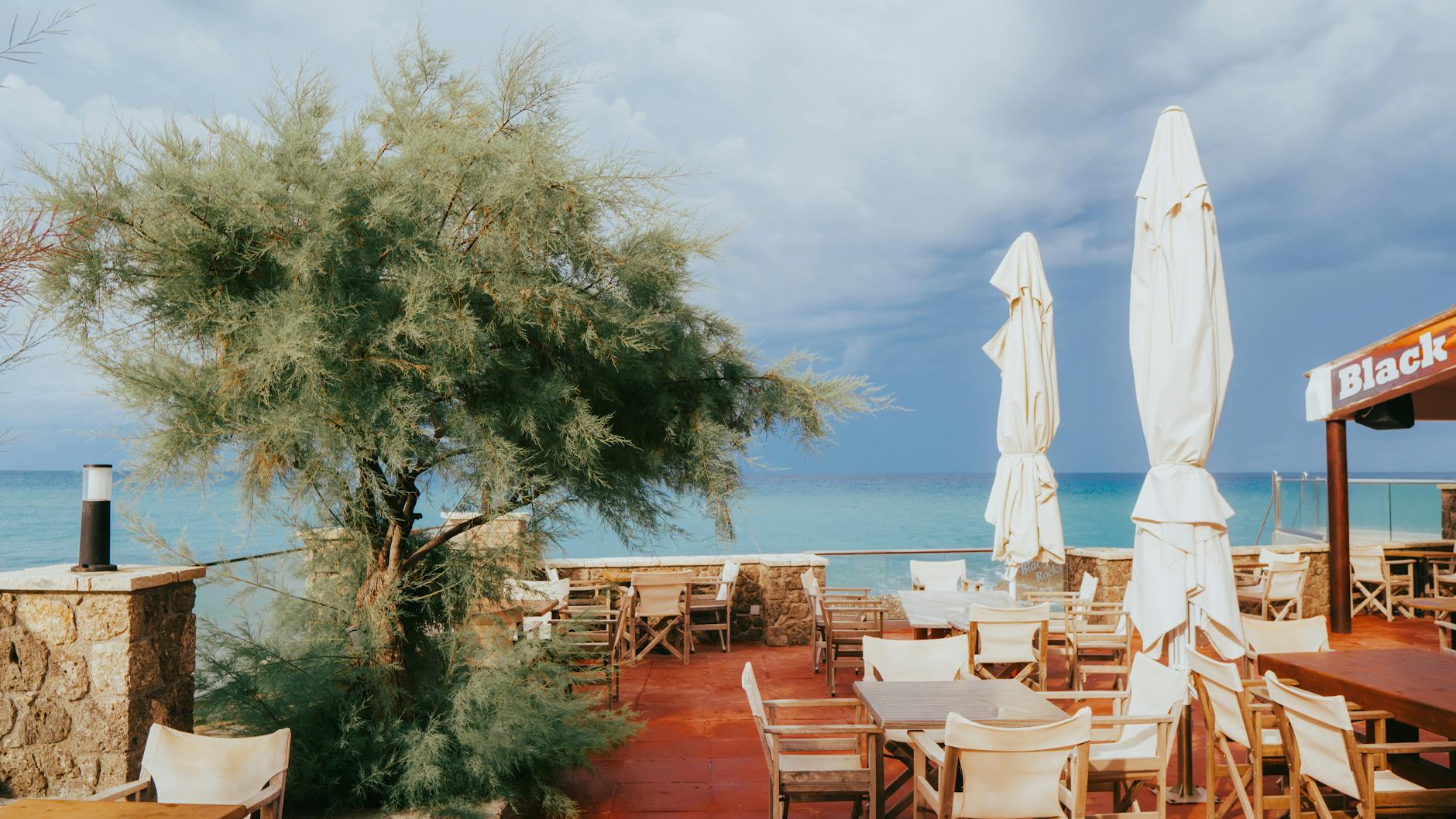 Empty beachside café with umbrellas and a view of the sea, ready for guests.